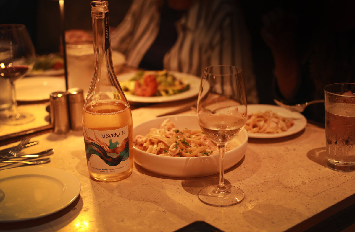 Dinner table with low, romantic lighting, wine and pasta dishes.